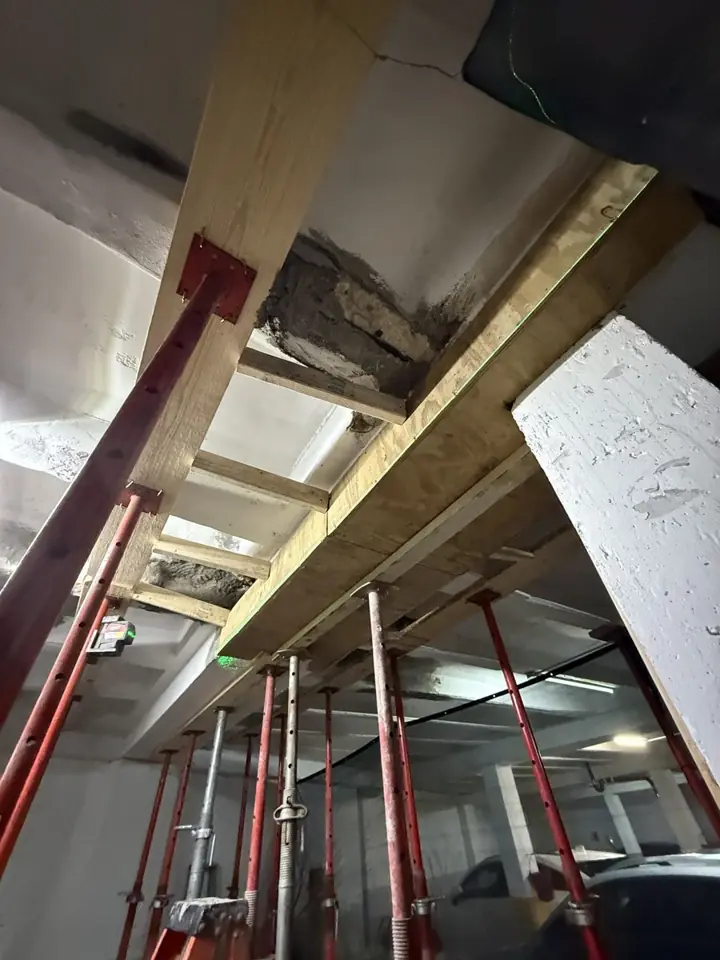 Parking garage beam shored with steel posts and timber during concrete restoration