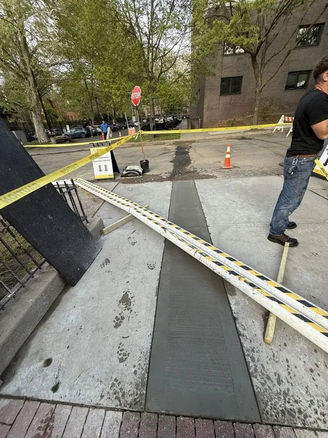 Crew finishing a new broom-finished concrete sidewalk strip